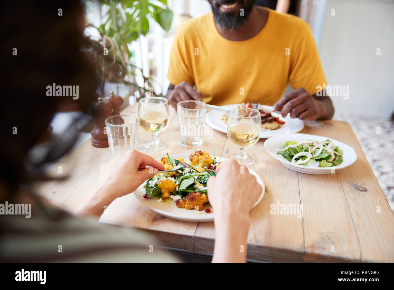 Couple eating at restaurant, over shoulder view, mid section Stock Photo