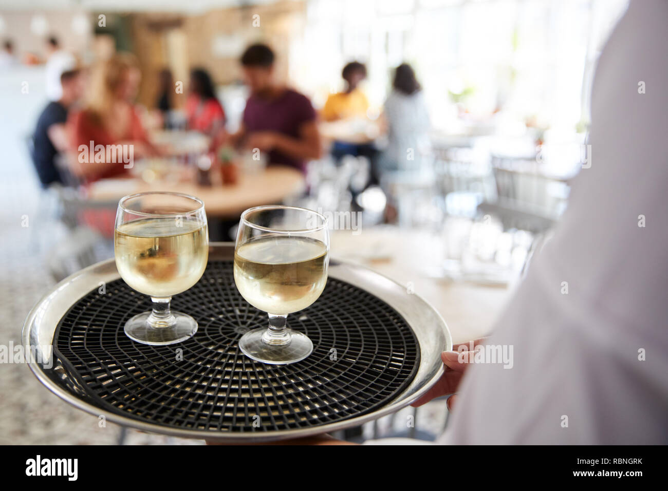 Tray with drinks carried by waiter at a restaurant, close up Stock Photo