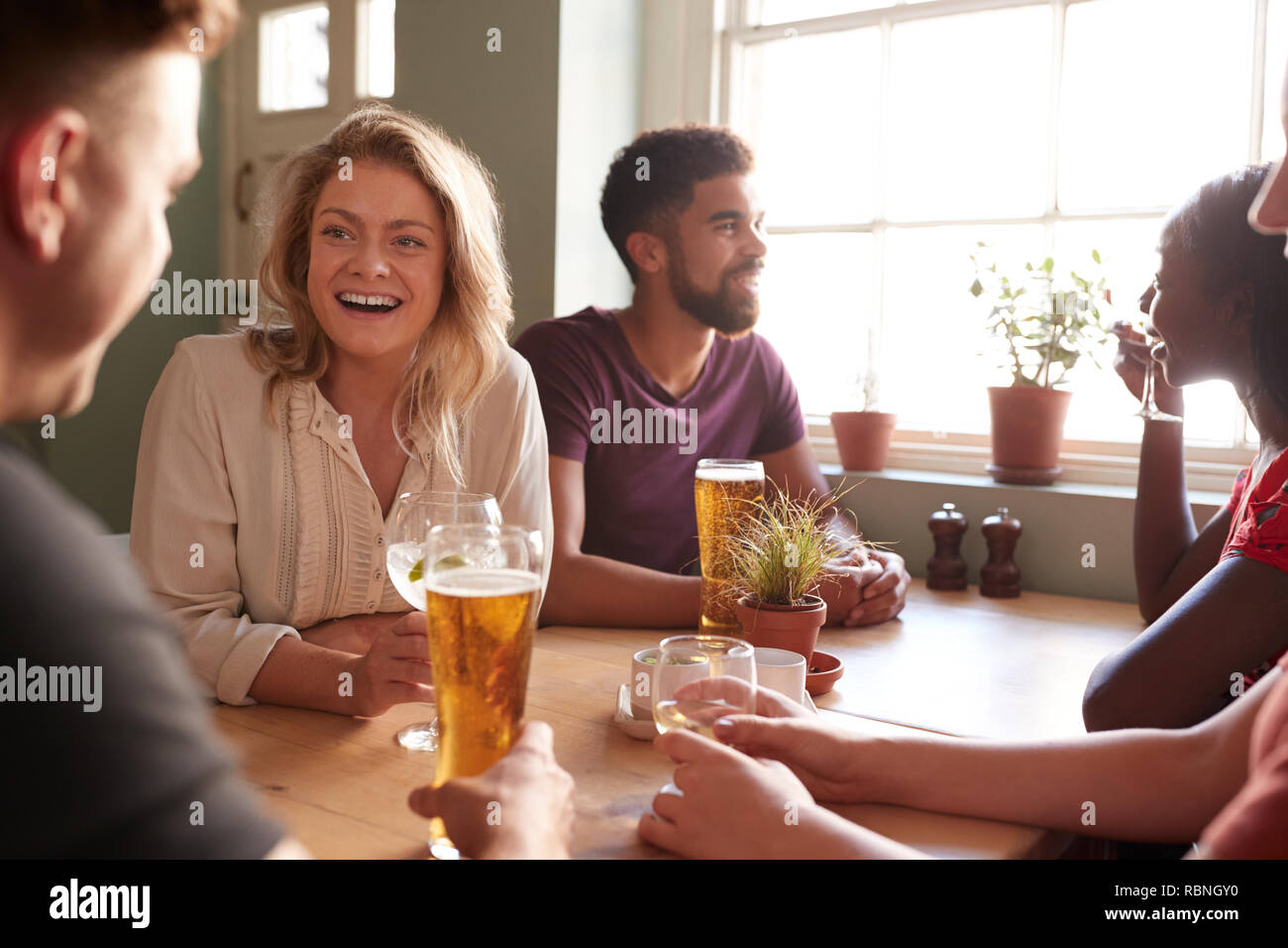 Young adult friends talking at a table in a pub Stock Photo