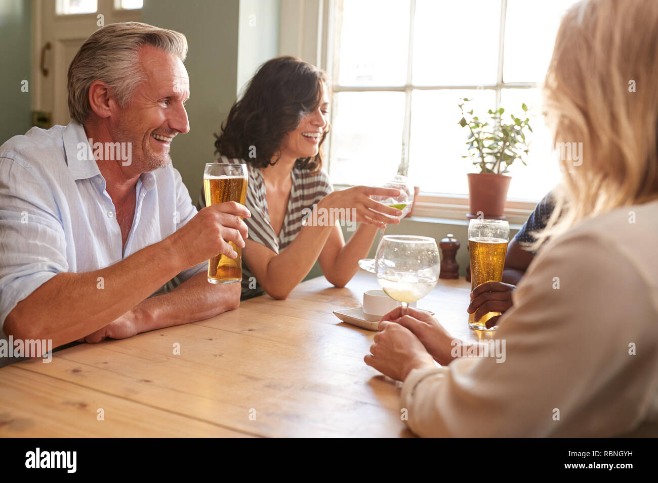 Mature adult friends drinking at a table in a pub Stock Photo