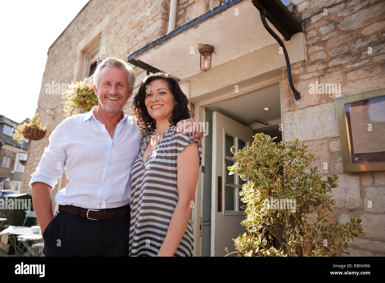 Mature business couple standing outside their restaurant pub Stock Photo