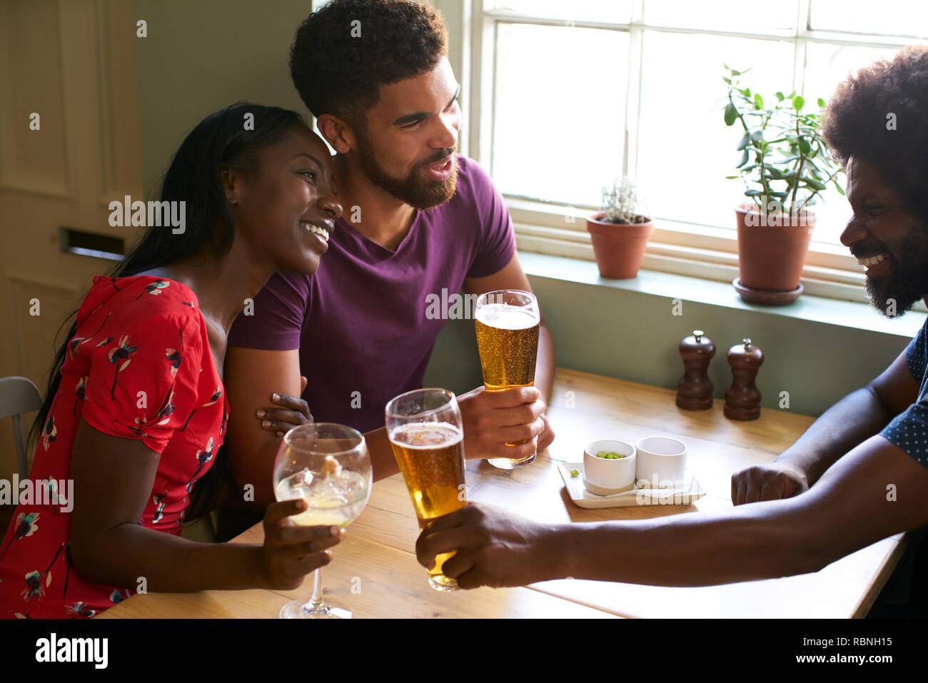 Young couple drinking with an older man in a pub Stock Photo