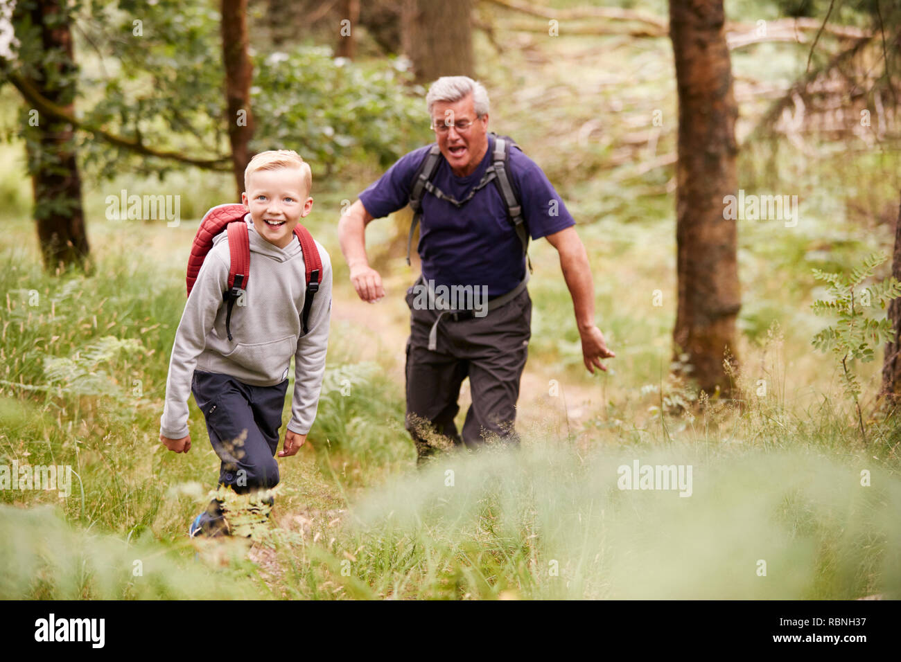 Grandfather and grandson hiking in a forest amongst greenery, selective focus Stock Photo