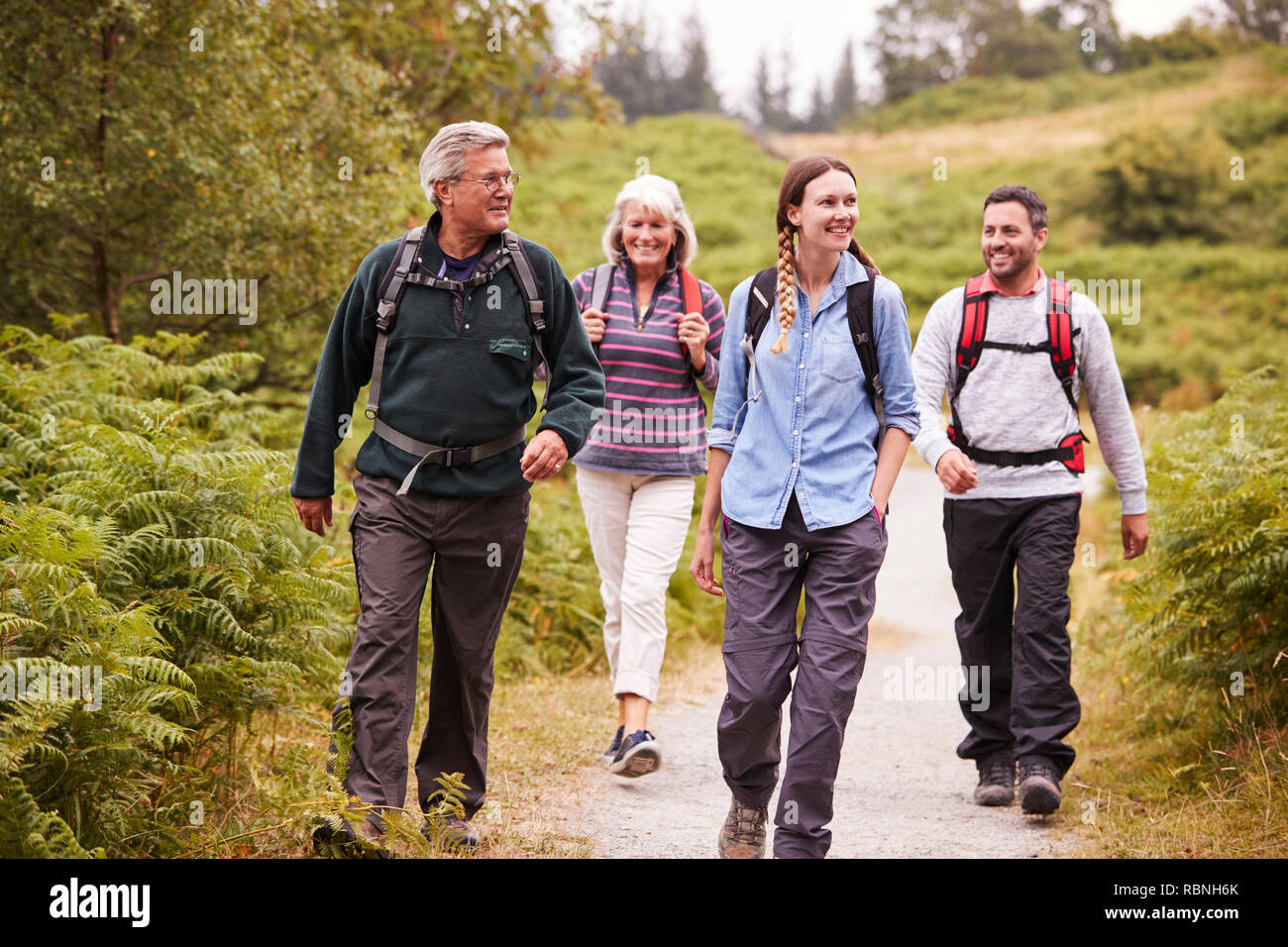 Two mixed age couples walking on a countryside path during family camping adventure, front view Stock Photo