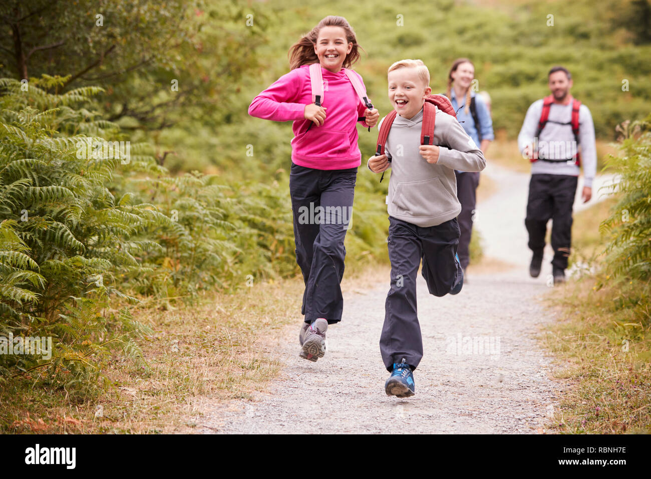 Children running ahead of parents, walking on a country path during a family camping trip, front view, close up Stock Photo