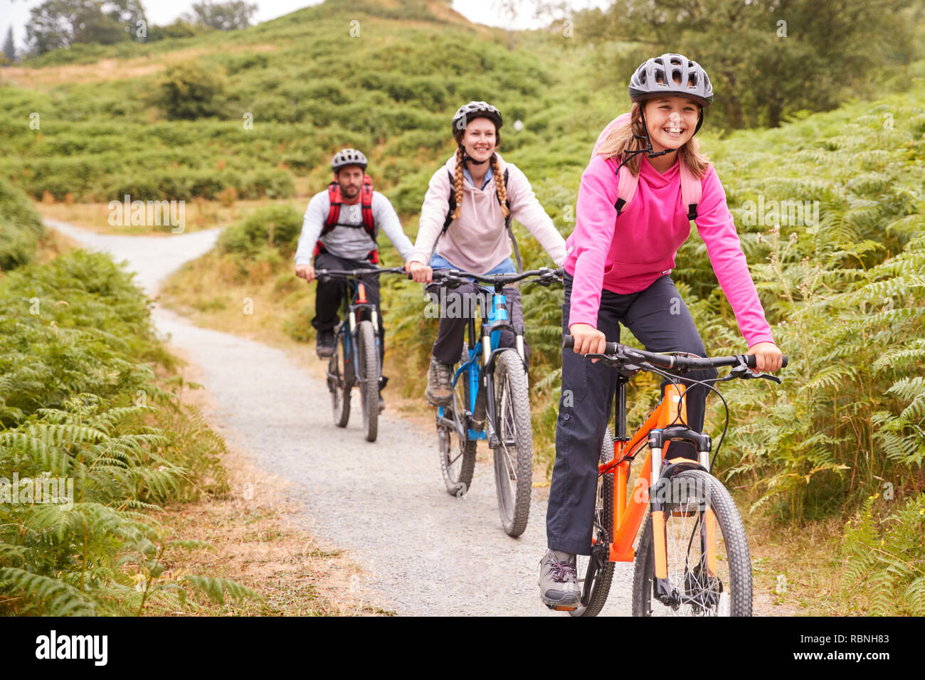Pre-teen girl riding mountain bike with her parents during a family camping trip, close up Stock Photo