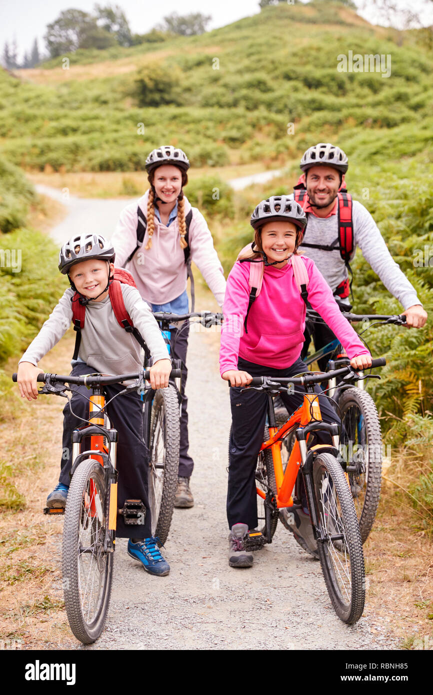 Parents and children sitting on mountain bikes in a country lane during a family camping trip, full length Stock Photo