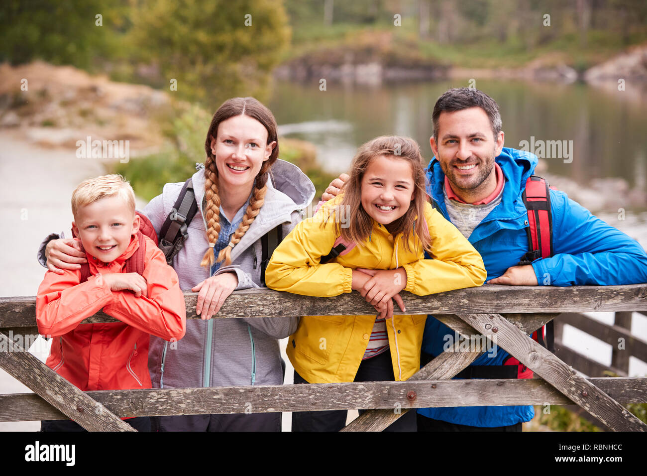 Young family leaning on a wooden fence in the countryside, looking at camera, close up Stock Photo