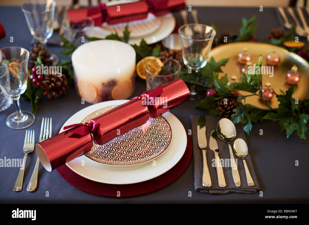 Close up of Christmas table setting with crackers arranged on plates and red and green table decorations, close up Stock Photo