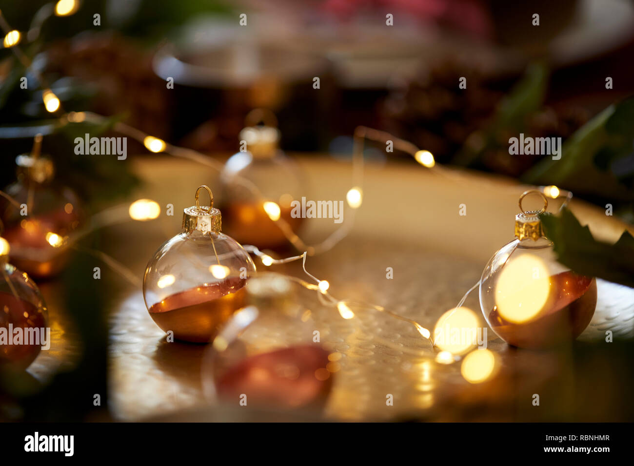 Close up of Christmas baubles on a gold table with warm glow, selective focus Stock Photo