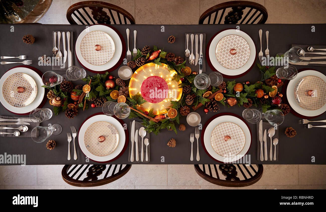 Christmas table setting with baubles arranged on plates and green and red table decorations, overhead view Stock Photo