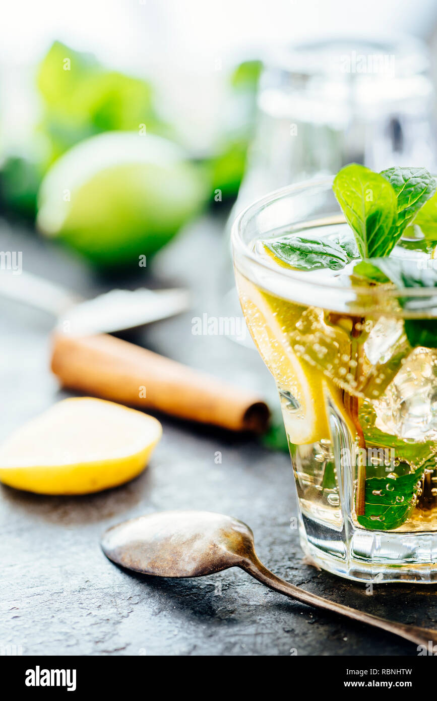 Mojito cocktail making at bar. Cocktail ingredients for summer party refreshment drink preparation. Lime, mint, sugar, vodka and gin on dark rustic ba Stock Photo