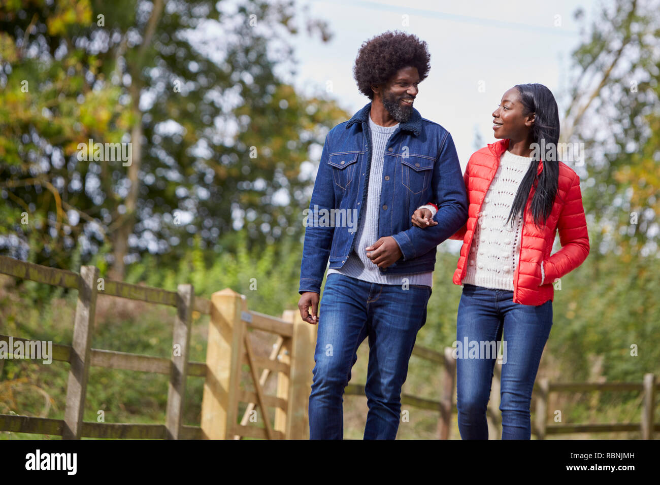 Black adult couple talking and walking  arm in arm in the countryside Stock Photo