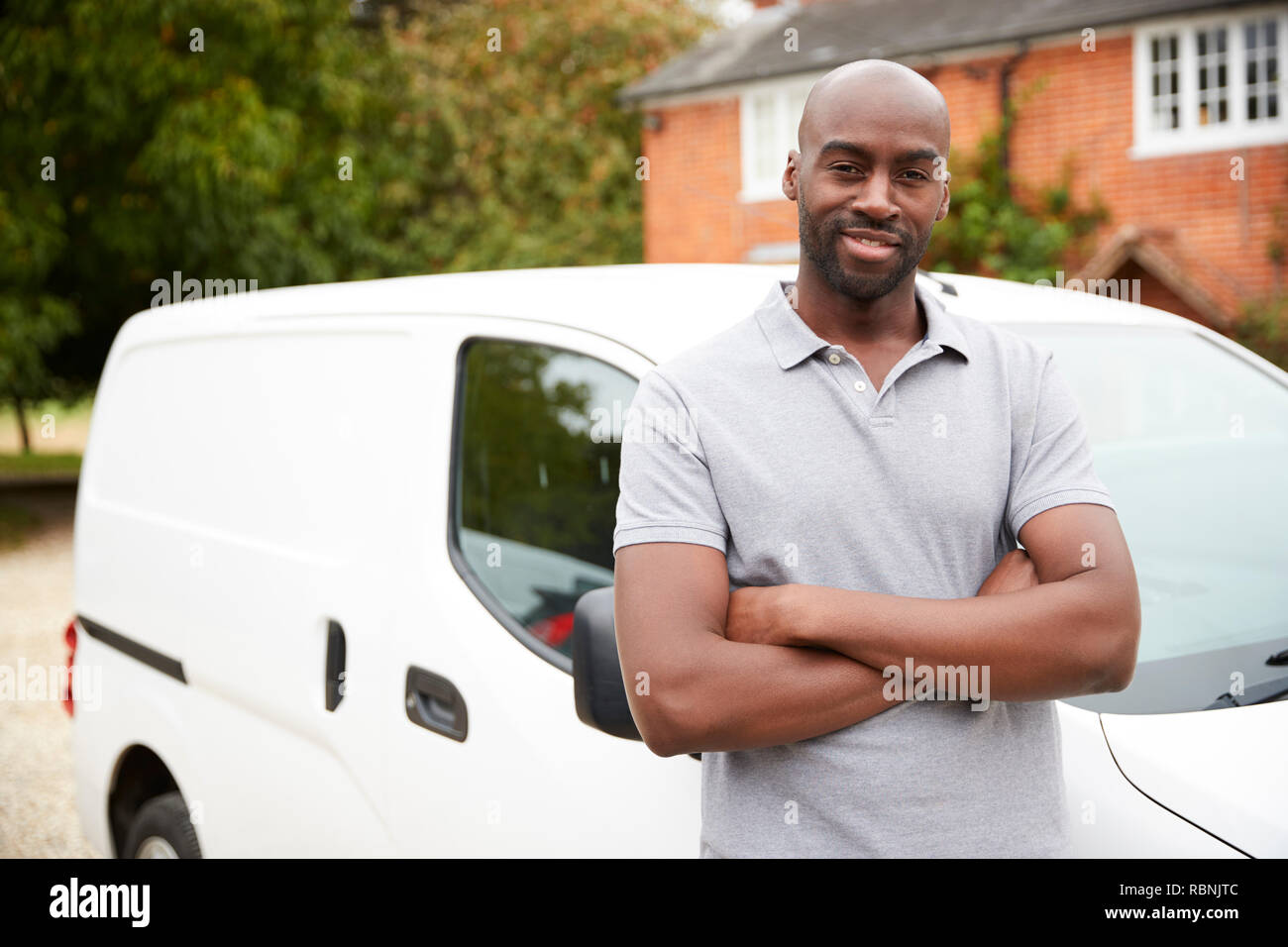 Young black adult tradesman standing next to his white van, close up, close up Stock Photo