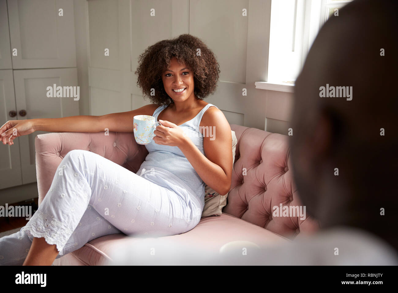 Young adult black couple sit drinking coffee looking at each other in the morning, over shoulder view, close up Stock Photo