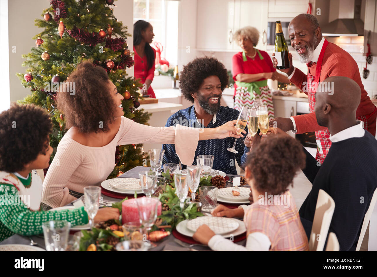 Family talking and raising glasses at the dinner table during a multi generation, mixed race family Christmas celebration Stock Photo