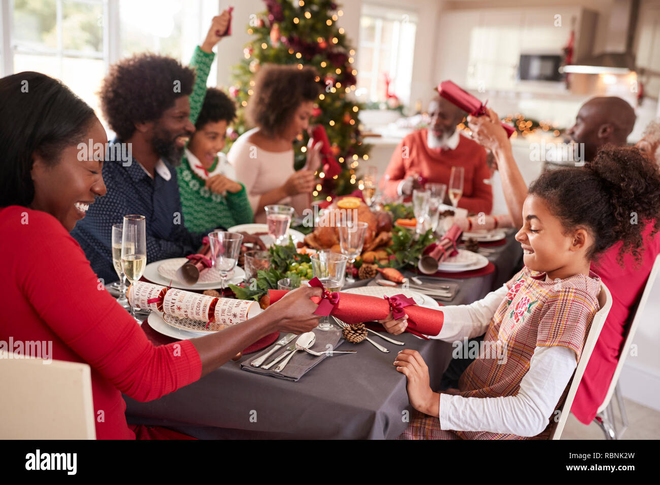 Mixed race, multi generation family having fun pulling crackers at the Christmas dinner table Stock Photo