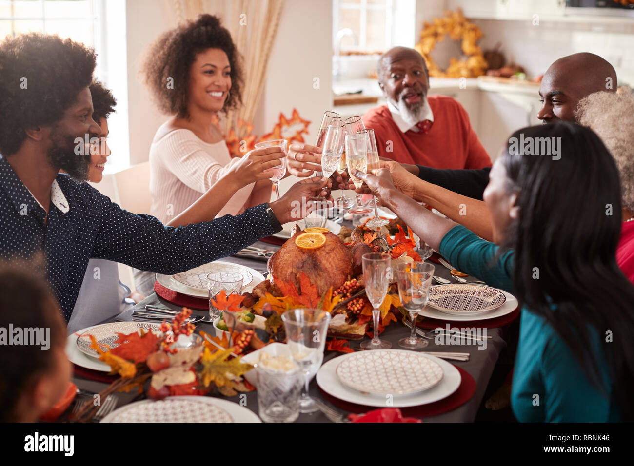 Multi generation mixed race family raise their glasses to make a toast at their Thanksgiving dinner table Stock Photo
