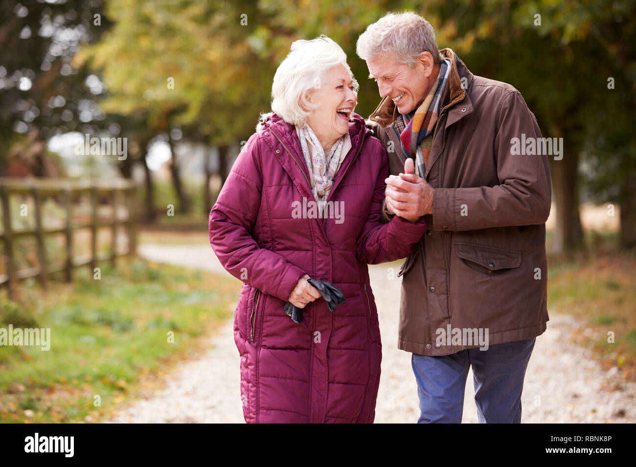 Active Senior Couple On Autumn Walk On Path Through Countryside Stock Photo
