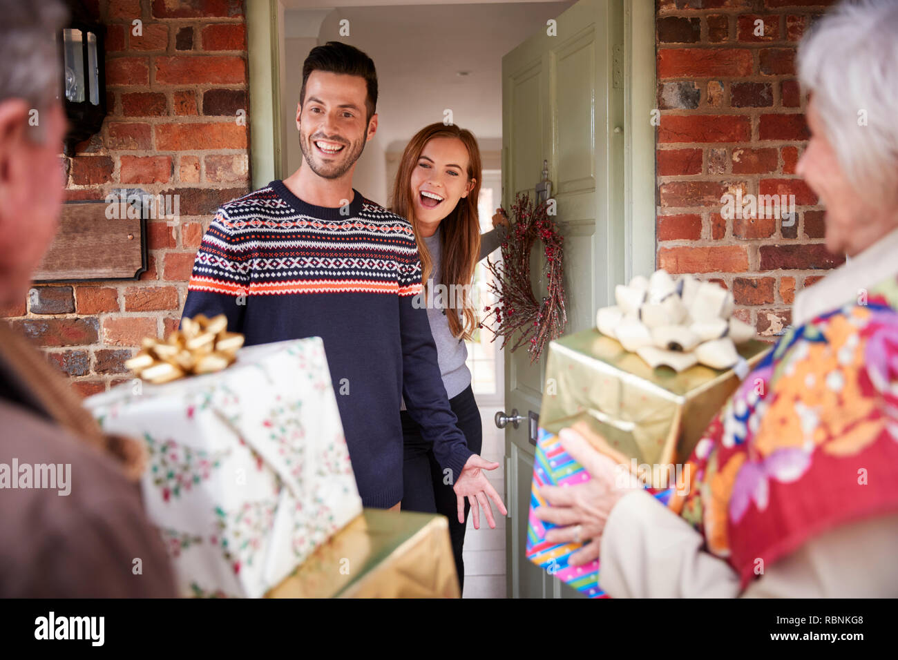 Senior Parents Being Greeted By Adult Offspring As They Arrive For Visit On Christmas Day Stock Photo