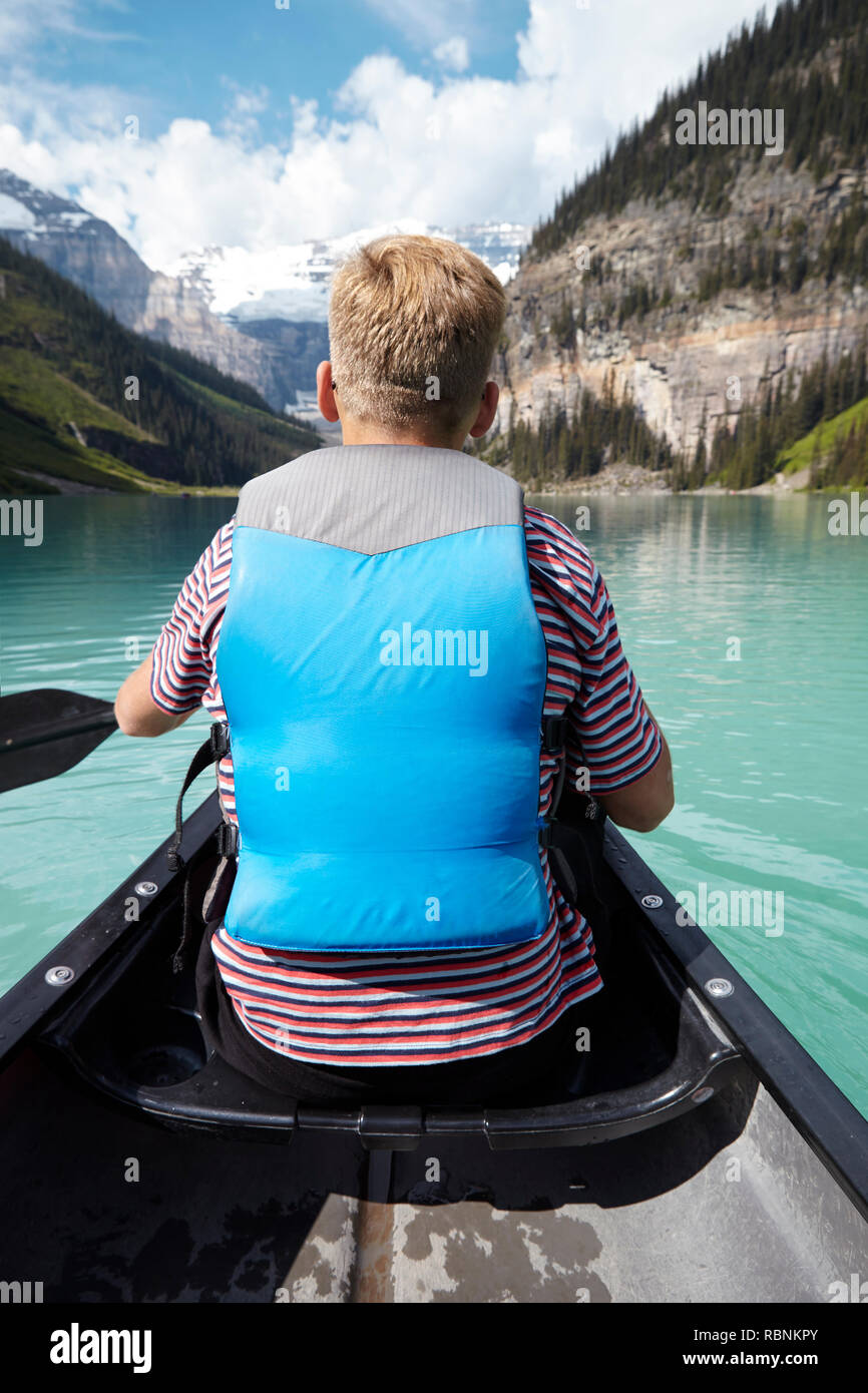 Rear View Of Man Kayaking On Beautiful Lake In Alaska Stock Photo