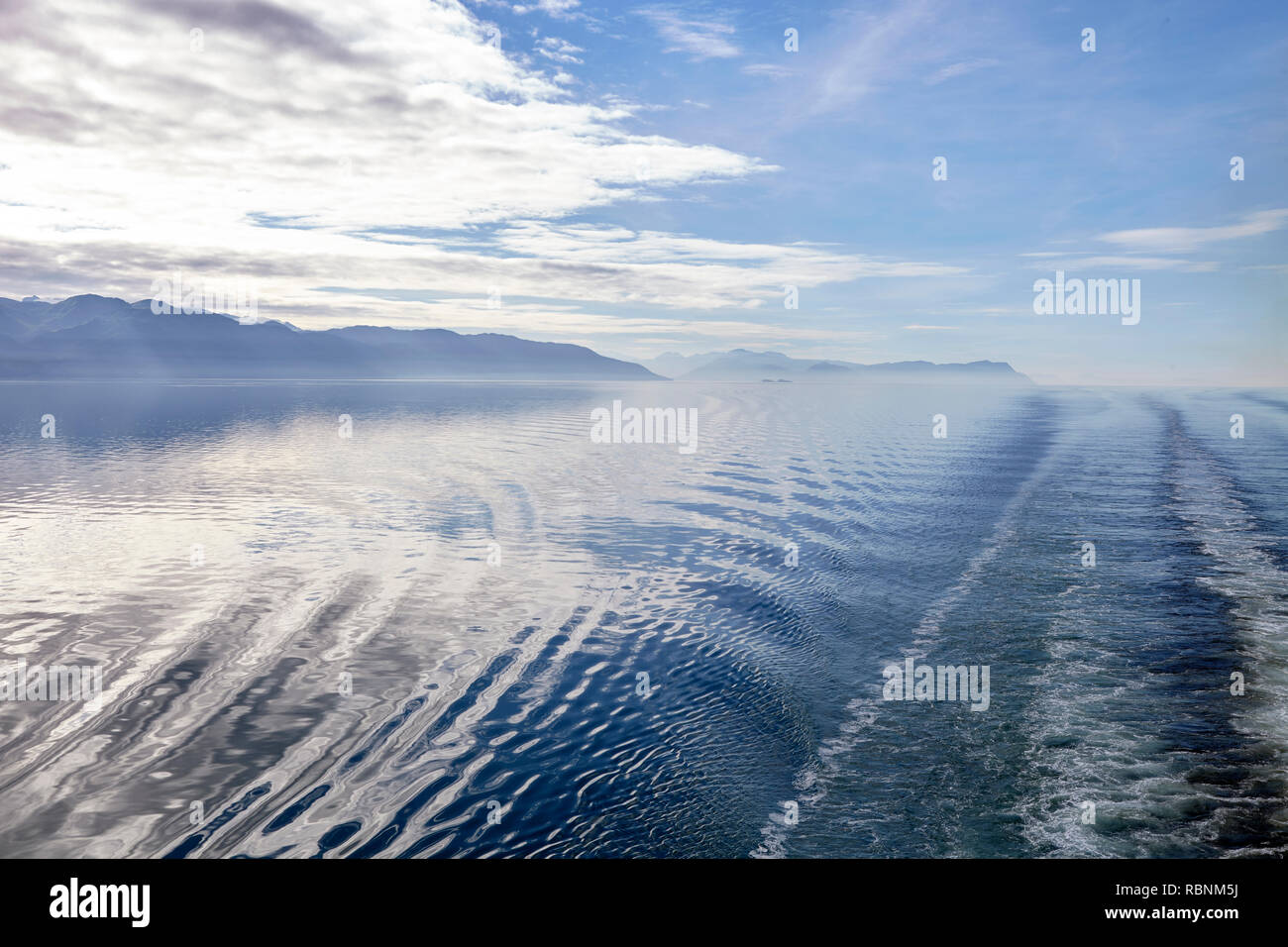 Wake Of Boat On Lake In Alaska Surrounded By Mountains And Forests Stock Photo