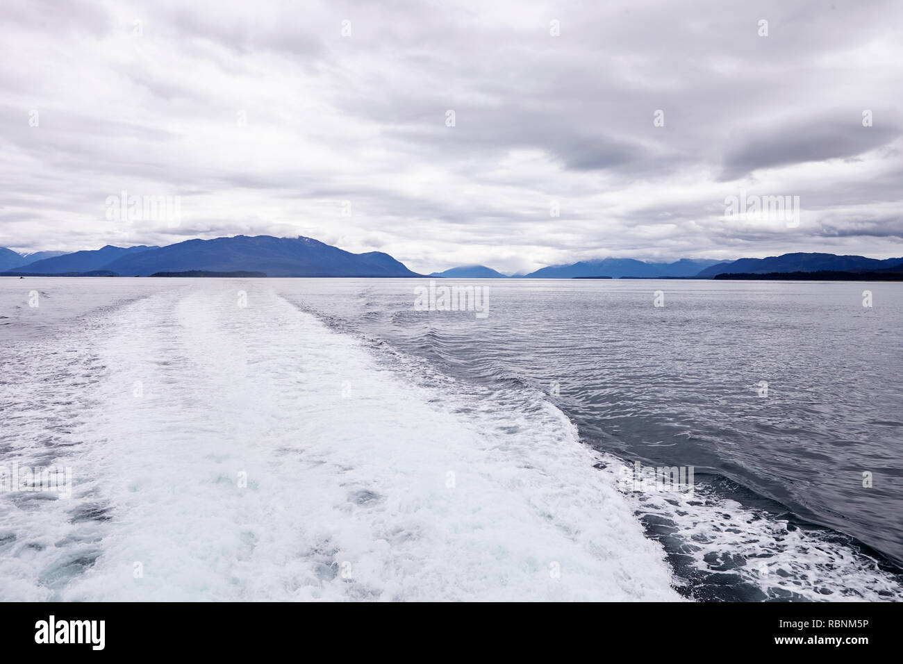 Wake Of Boat On Lake In Alaska Surrounded By Mountains And Forests Stock Photo