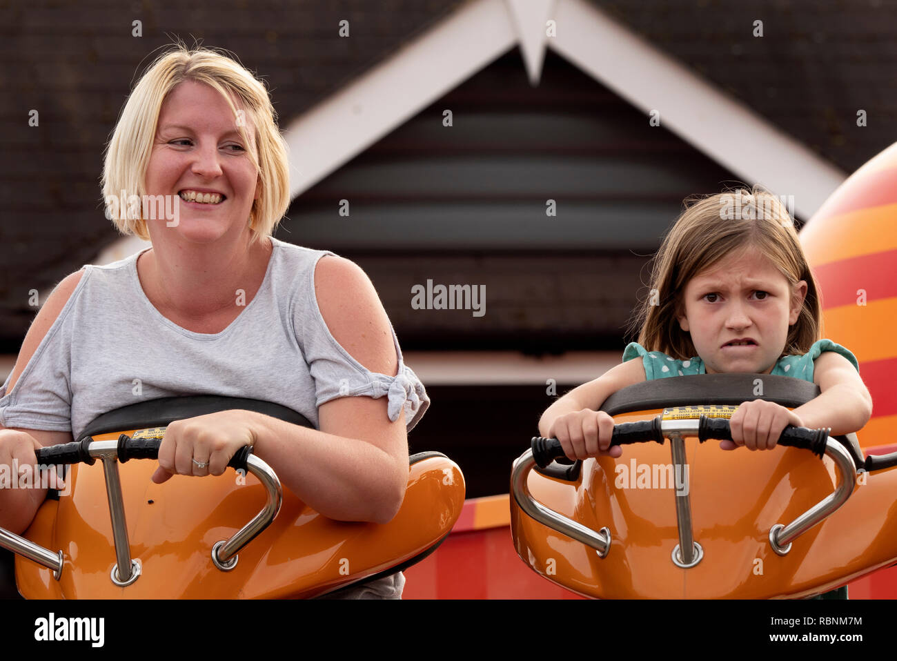 Mother and 7 year daughter having fun on pleasure park ride. Stock Photo