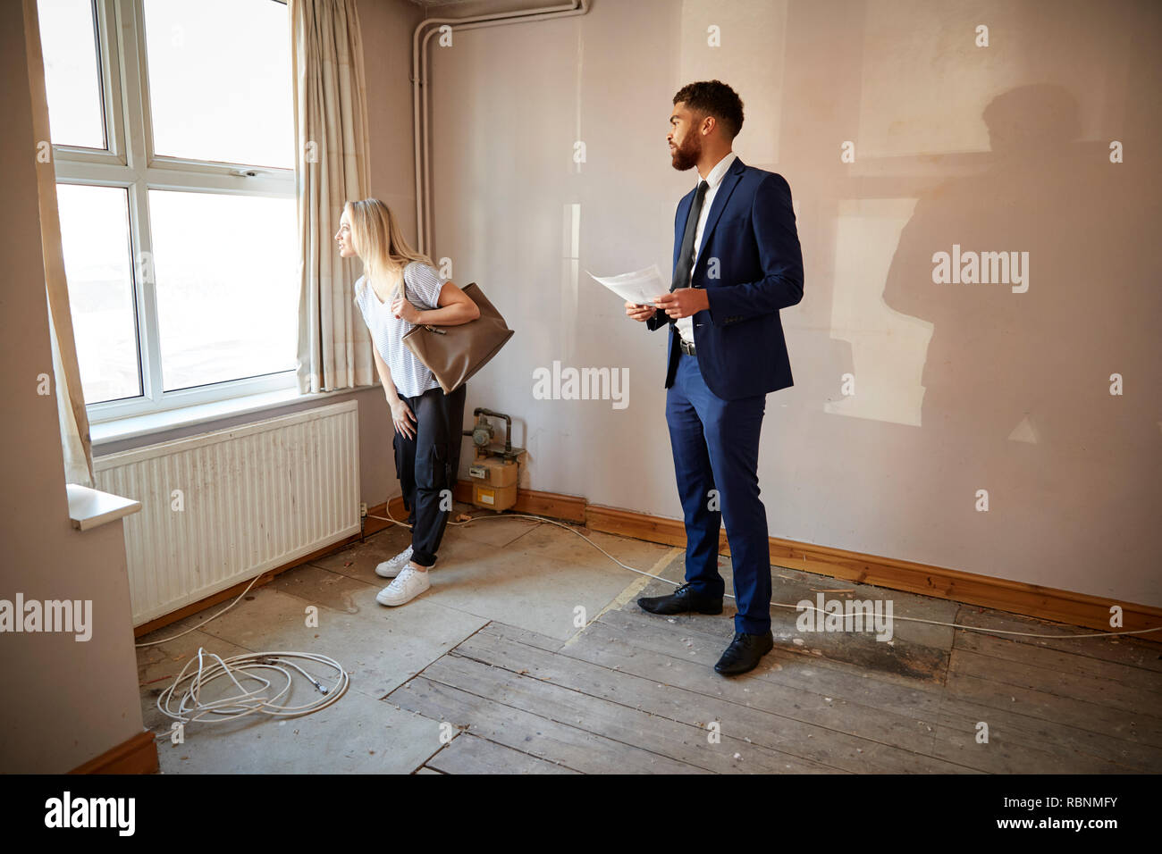 Female First Time Buyer Looking At House Survey With Realtor Stock Photo