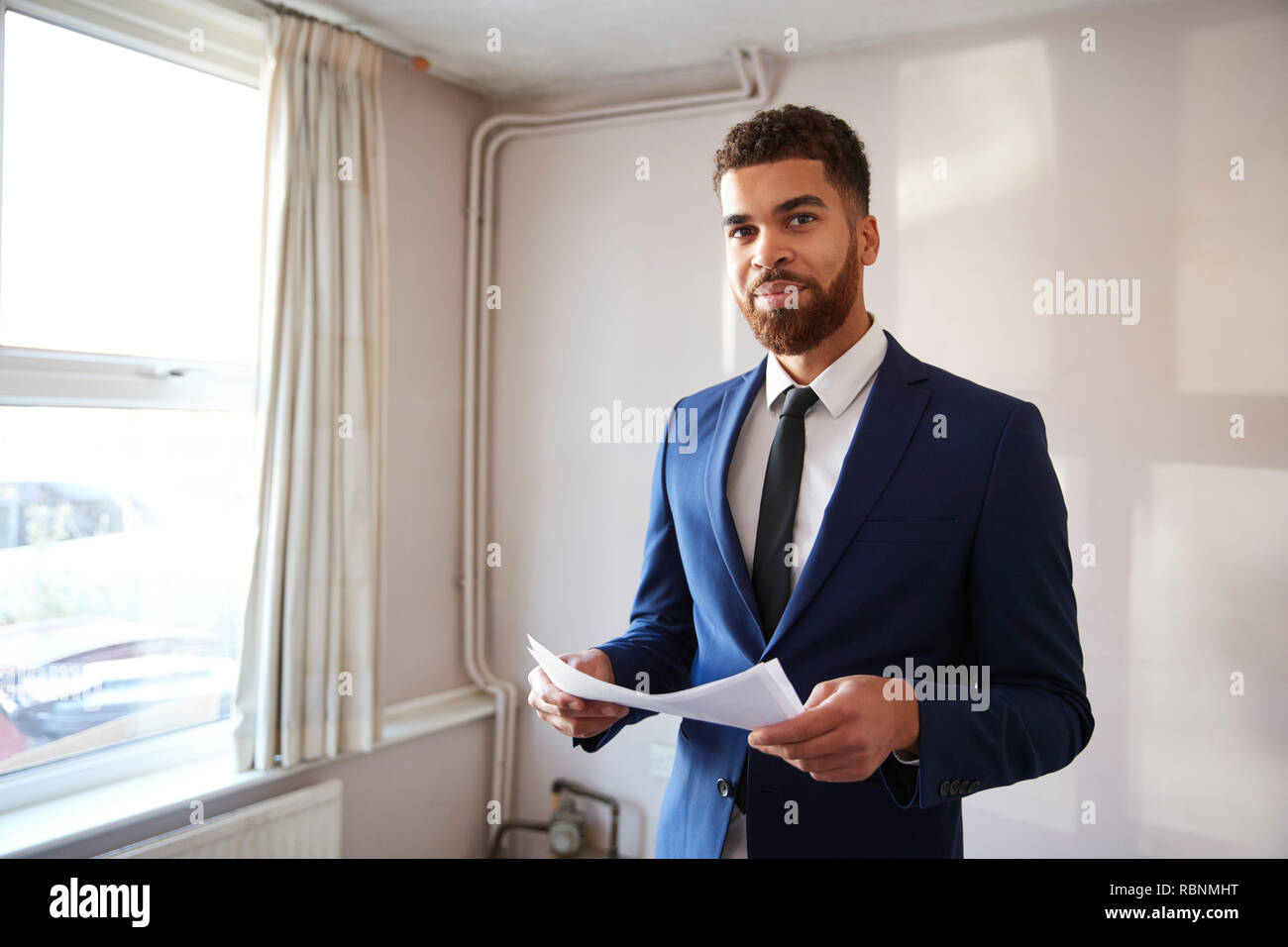 Portrait Of Male Realtor Looking At House Details In Property For Renovation Stock Photo