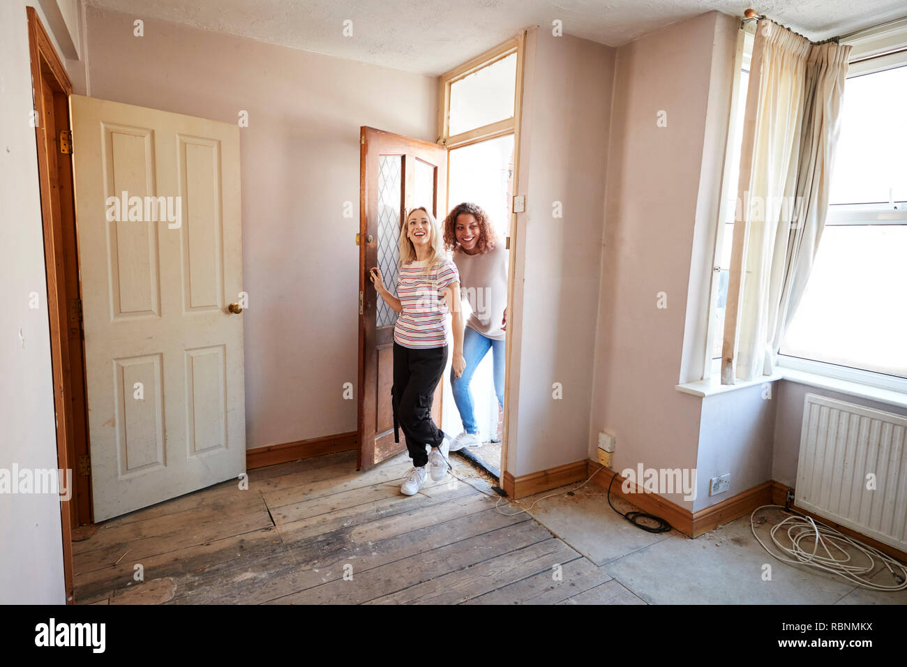 Excited Female Couple Opening Front Door Of New Home Stock Photo