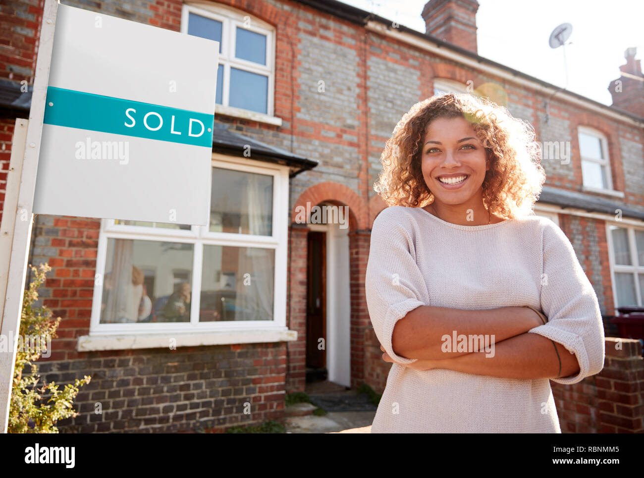 Portrait Of Excited Woman Standing Outside New Home With Sold Sign ...