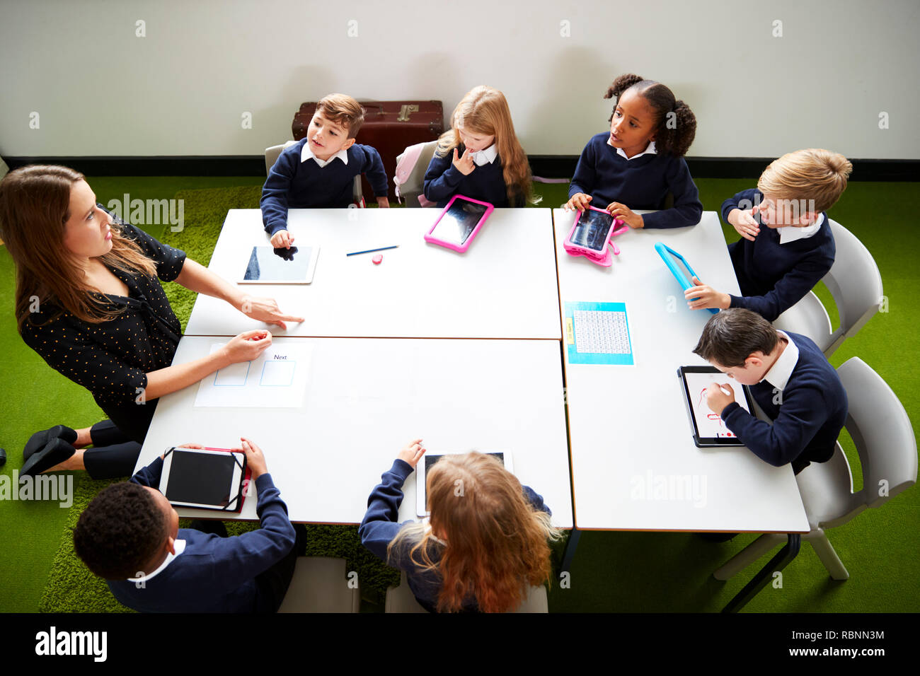 Elevated view of primary school kids sitting around a table in the classroom with their female