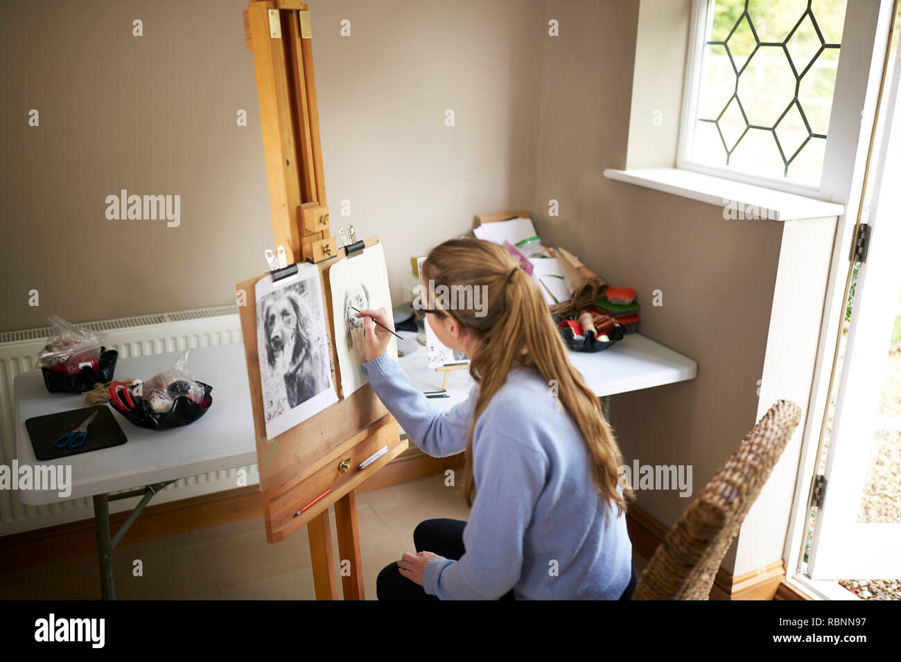 Rear View Of Female Teenage Artist Sitting At Easel Drawing Picture Of ...