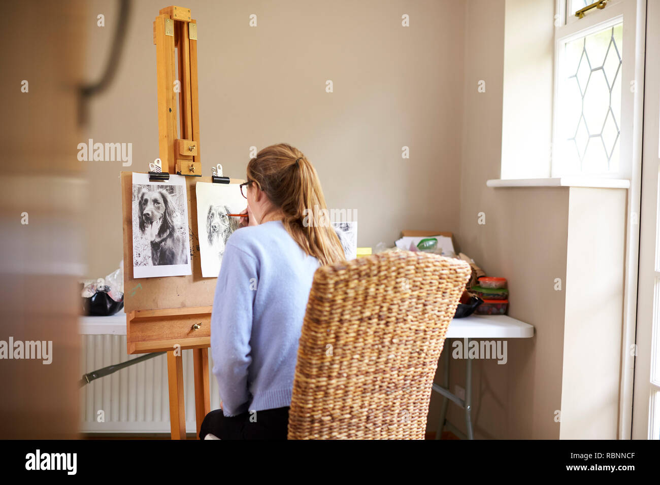 Rear View Of Female Teenage Artist Sitting At Easel Drawing Picture Of ...