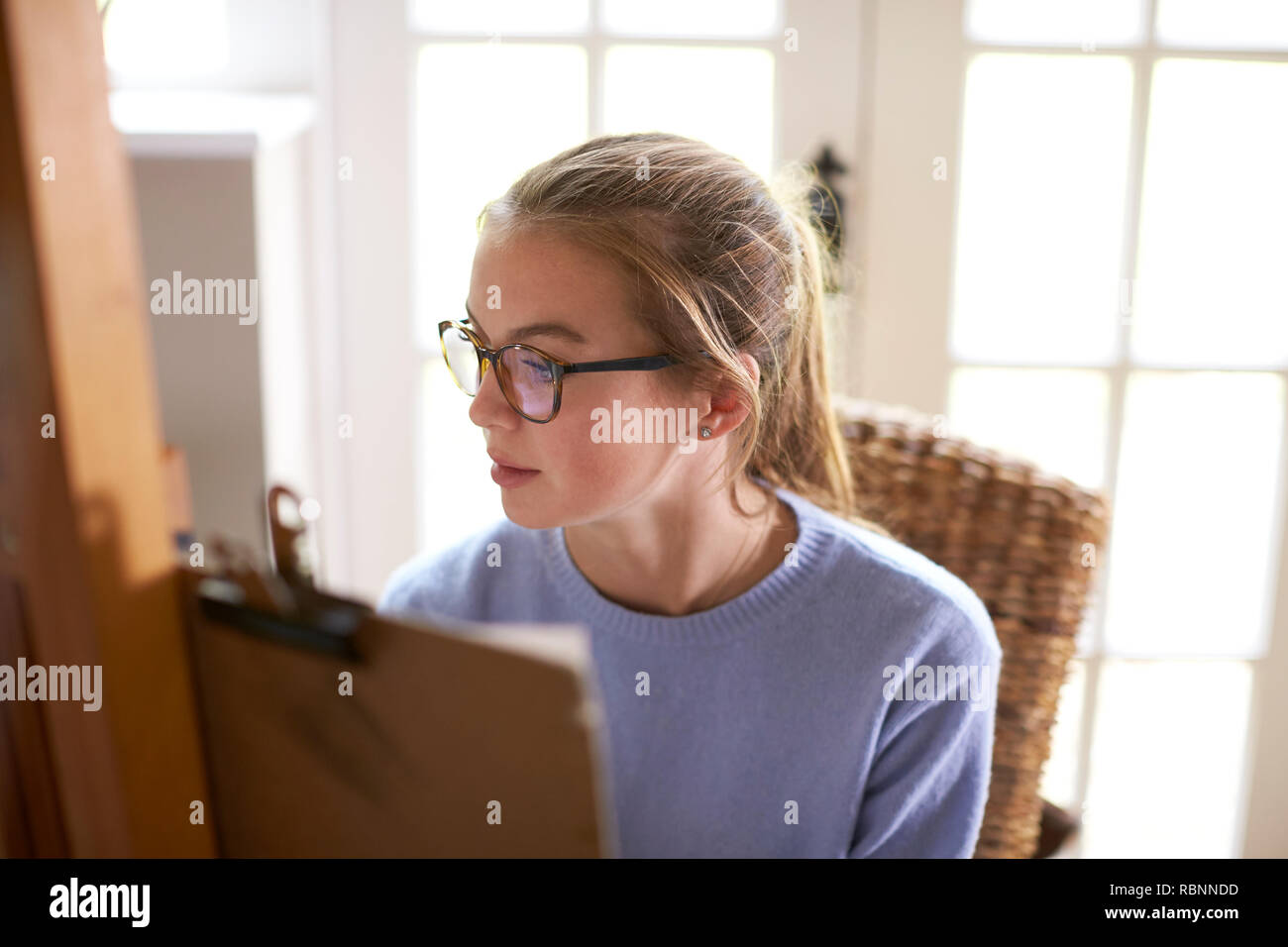 Close Up Of Female Teenage Artist Working Behind Easel Stock Photo