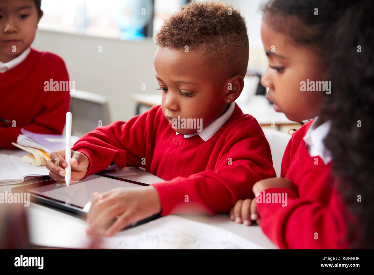 Three african kids playing together on tablet.