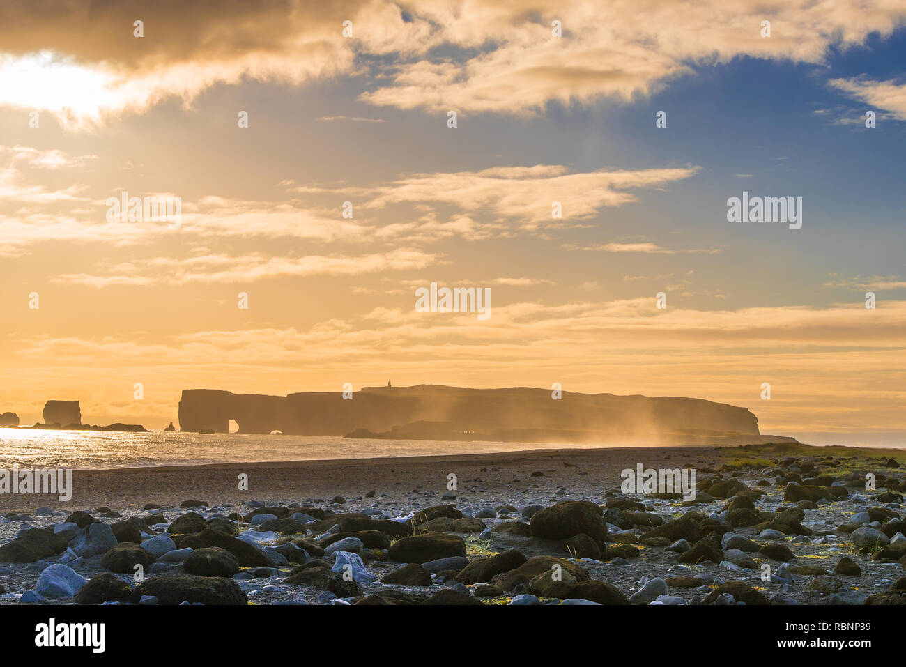 big flat rock in the ocean with surge in foreground in sunset mood Stock Photo