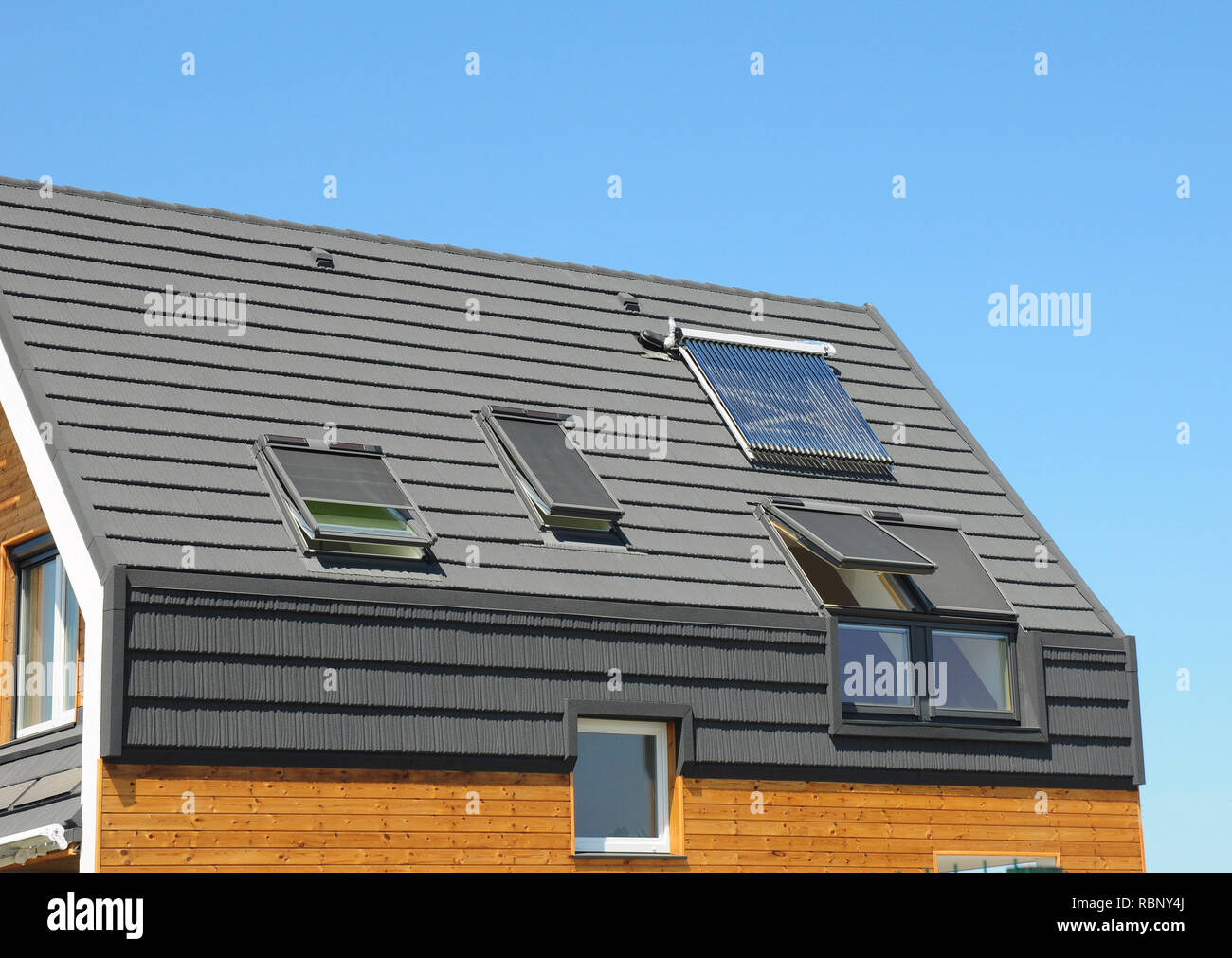 Solar panel and solar water heater  on the modern house roof with skylights and dormer outdoor for energy efficiency. Stock Photo
