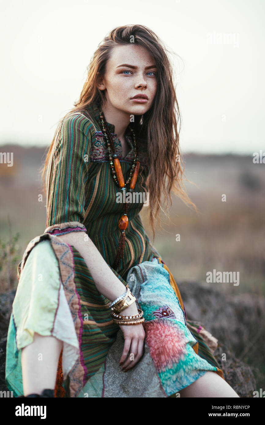 Fashion portrait of young hippie woman at sunset posing on nature background Stock Photo