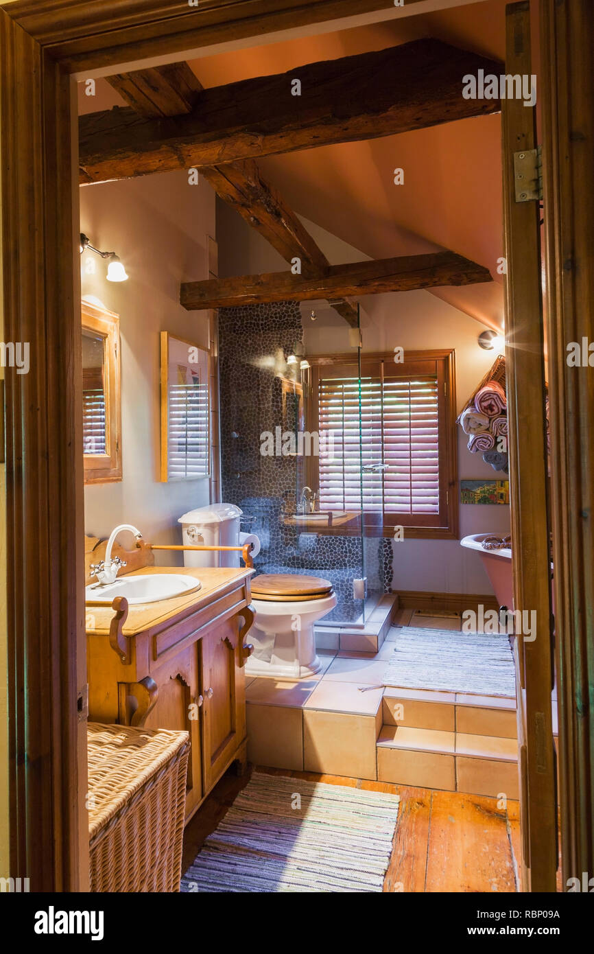Main bathroom with toilet and clawfoot bathtub on raised ceramic tile platform on upper floor