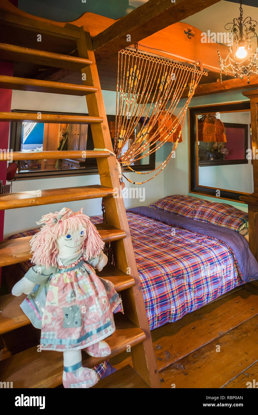 Ragdoll sitting on wooden bunkbed ladder in child's bedroom on the upstairs floor inside an old circa 1850 Canadiana cottage style home Stock Photo