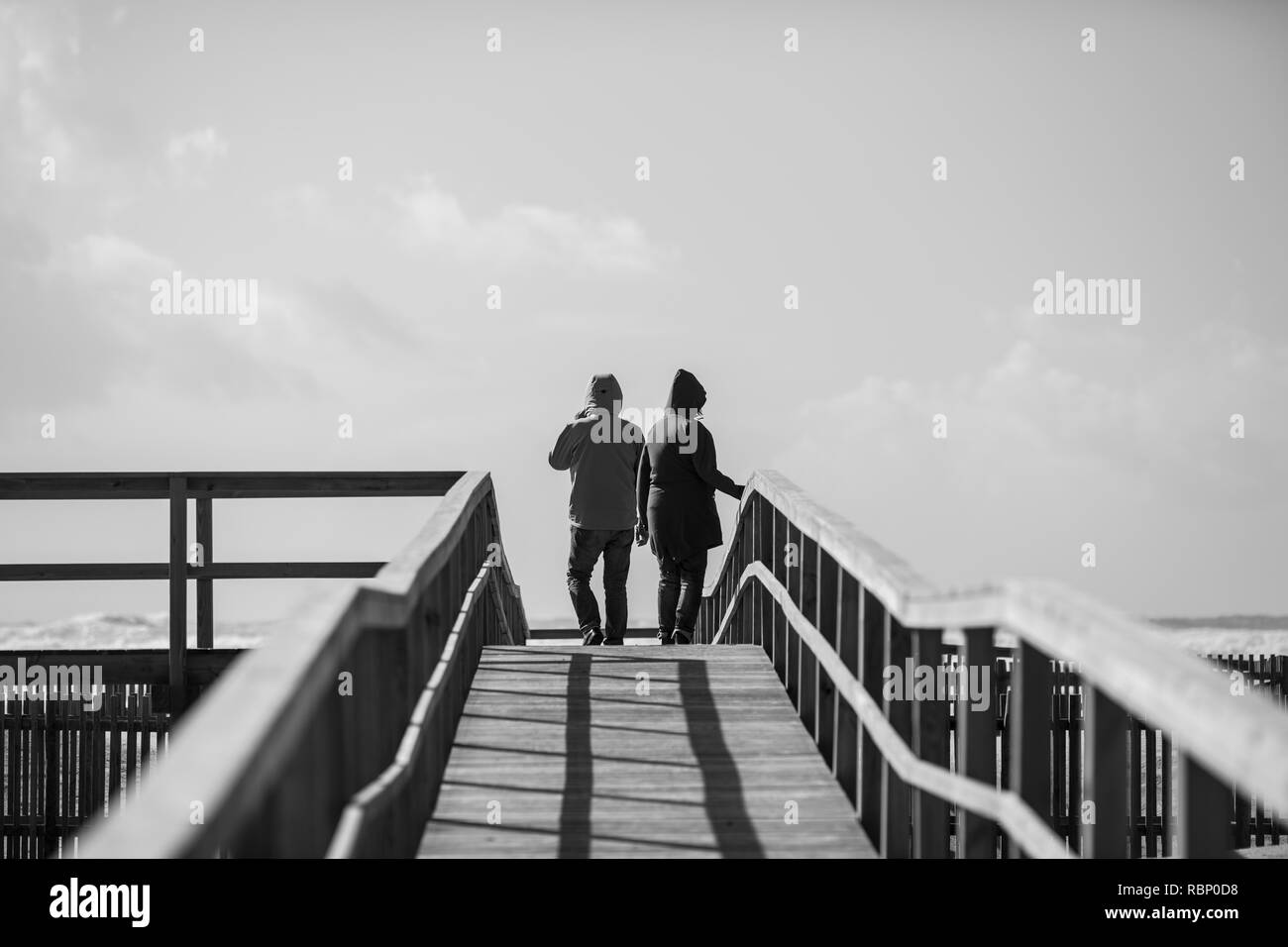 Rear view of man and woman walking on wooden boardwalk, Odeceixe, Portugal Stock Photo