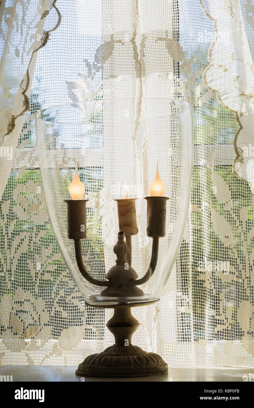 Antique electric candle light bulb holder on windowsil and white lace