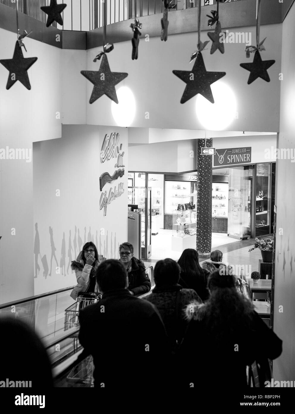 FRANKFURT, GERMANY - DEC 21, 2016: People on escalator with multiple decorations stars above commuting in shopping centre Stock Photo