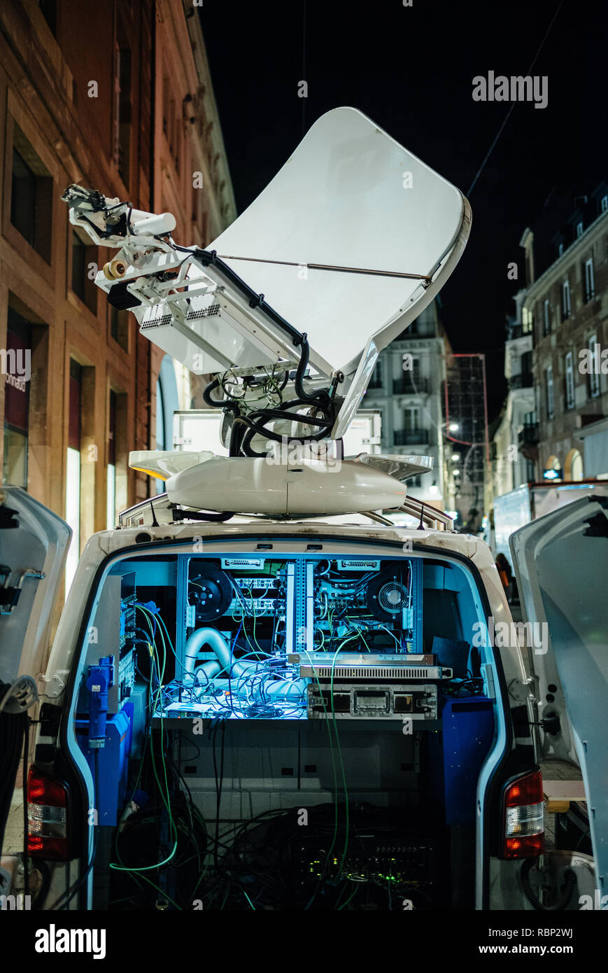 Opened door of parked satellite TV van transmitting breaking news events to satellites for broadcast around the world at night in city Stock Photo