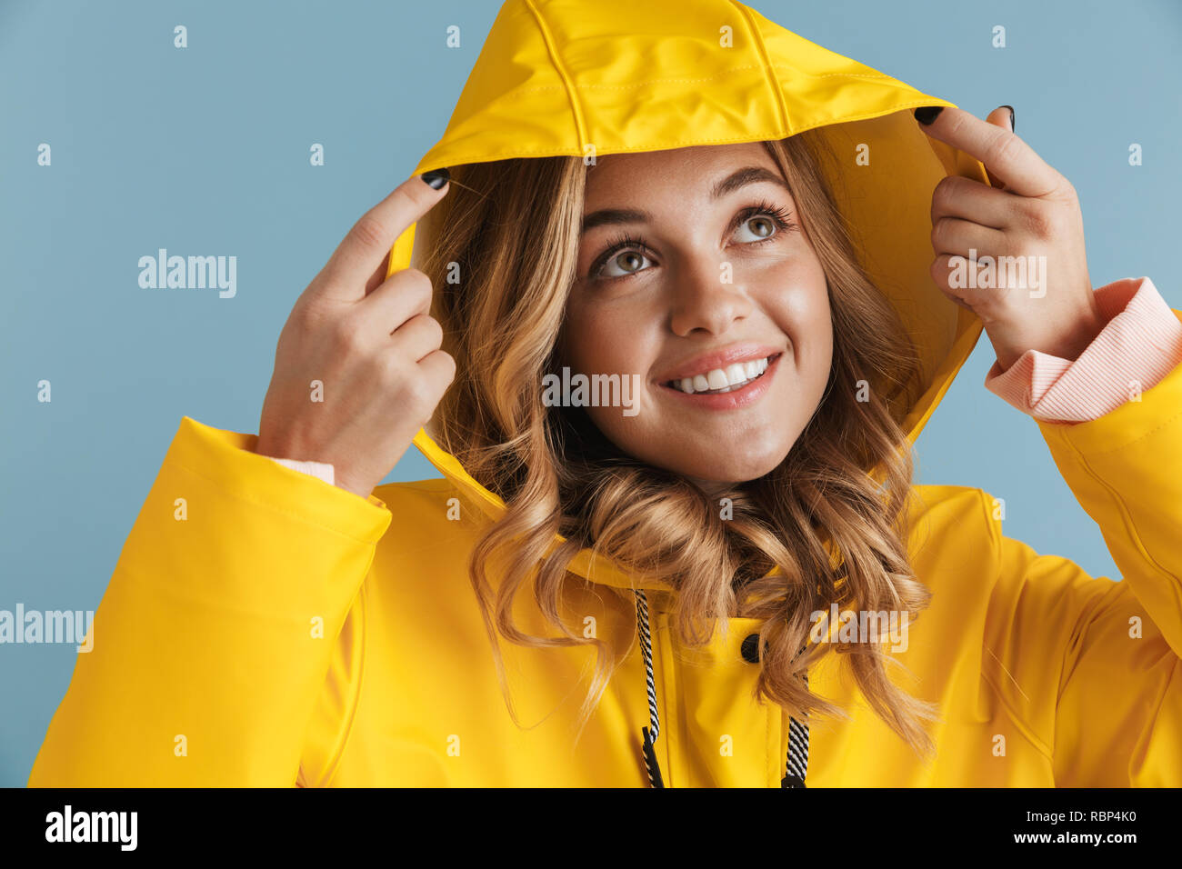Photo of adorable woman 20s wearing yellow raincoat looking upward