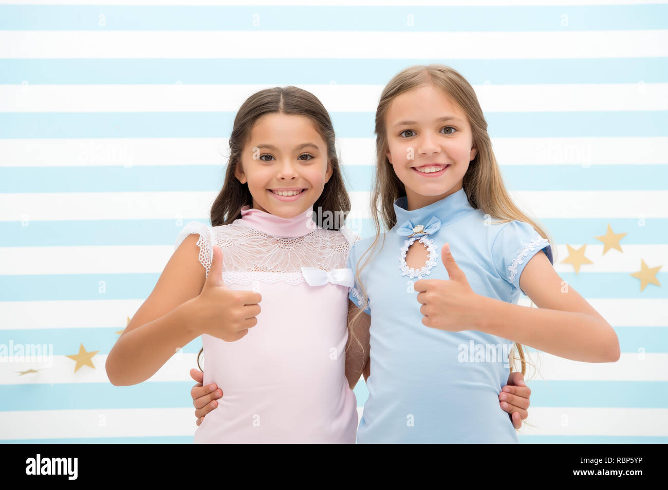 Girls smiling happy faces hug each other and show thumbs up gesture. Girls children best friends hugs. Happy childhood concept. Kids schoolgirls preteens happy together. Friendship from childhood. Stock Photo