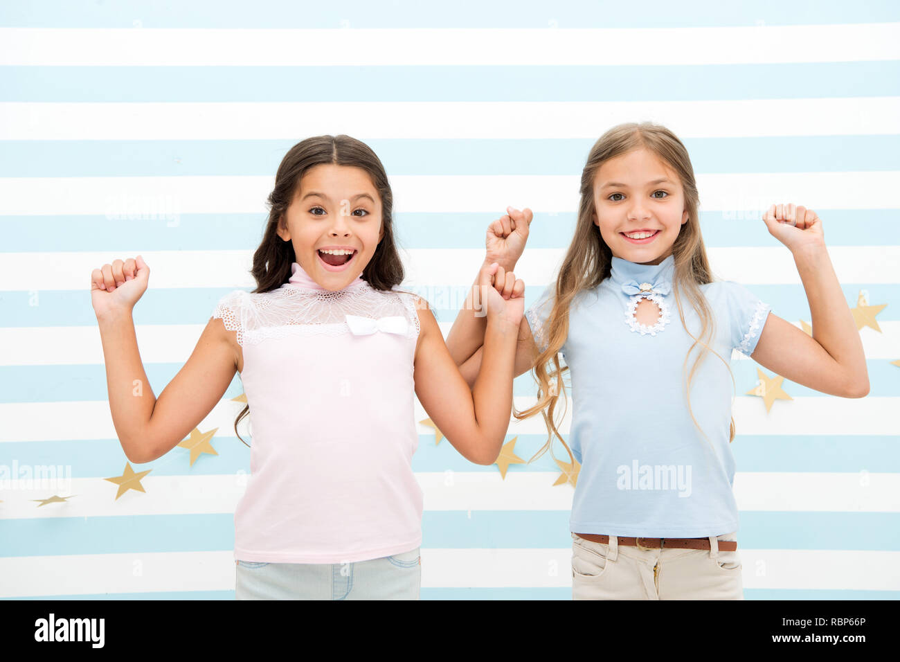 Thrilled moments together. Kids schoolgirls preteens happy together. Girls smiling happy faces excited expression stand striped background. Girls children best friends thrilled about surprising news. Stock Photo
