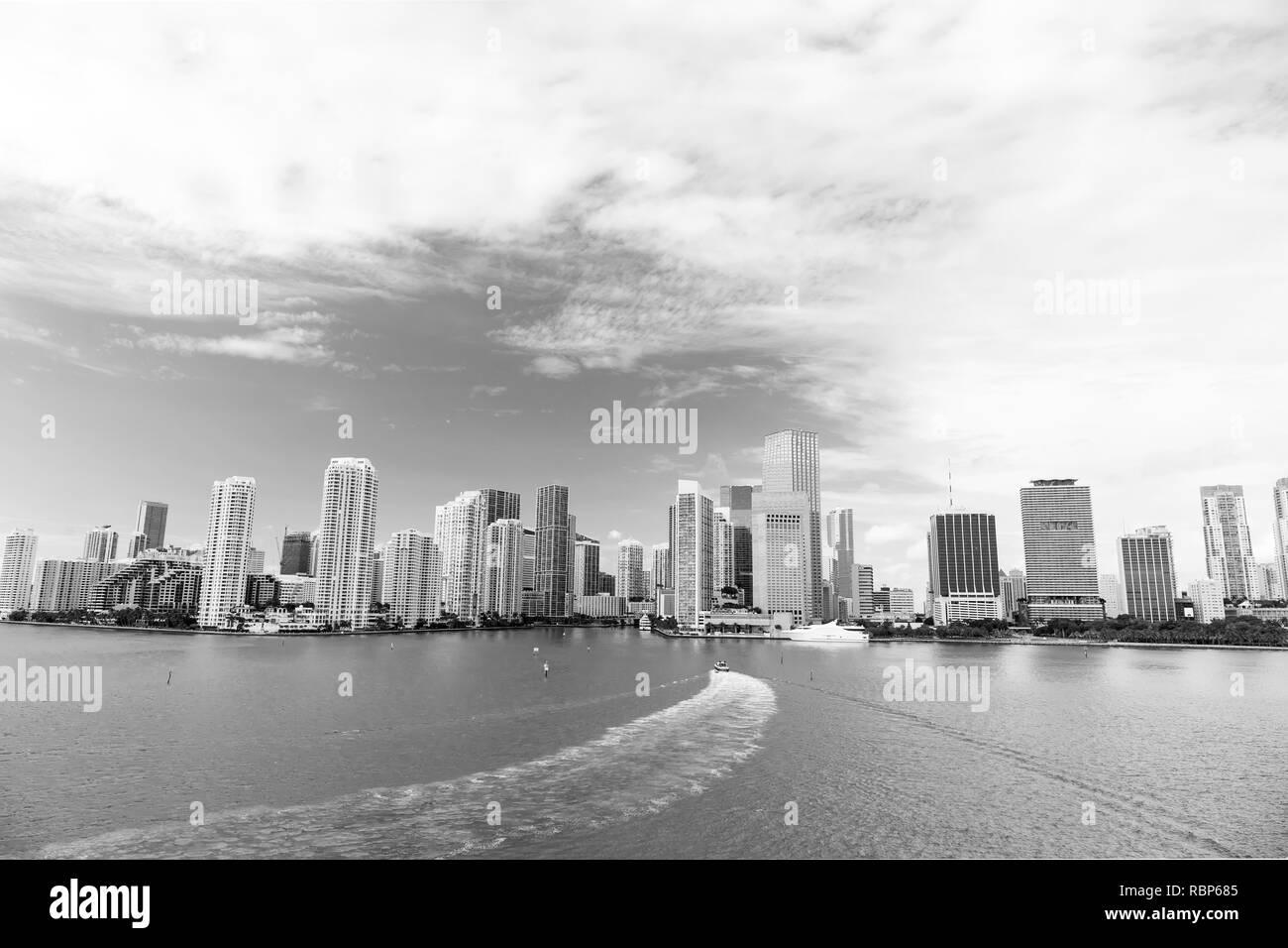 Aerial view of Miami skyscrapers with blue cloudy sky, white boat sailing next to Miami downtown